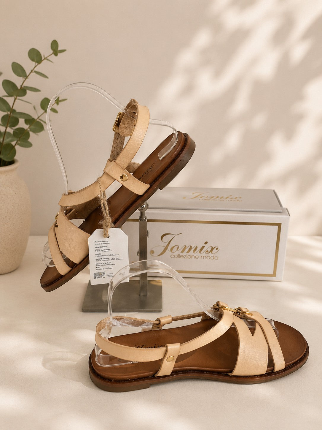 Sandales plates Frippindealz Jomix crème en simili cuir avec brides croisées et boucles dorées sur fond neutre