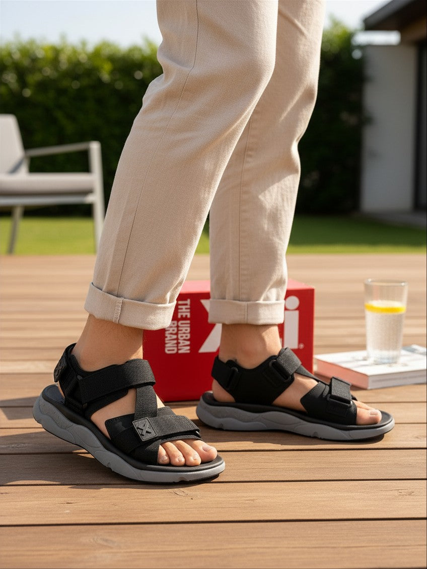 Sandales de sport Frippindealz XTI noires en textile avec brides à scratch et semelle crantée grise portées