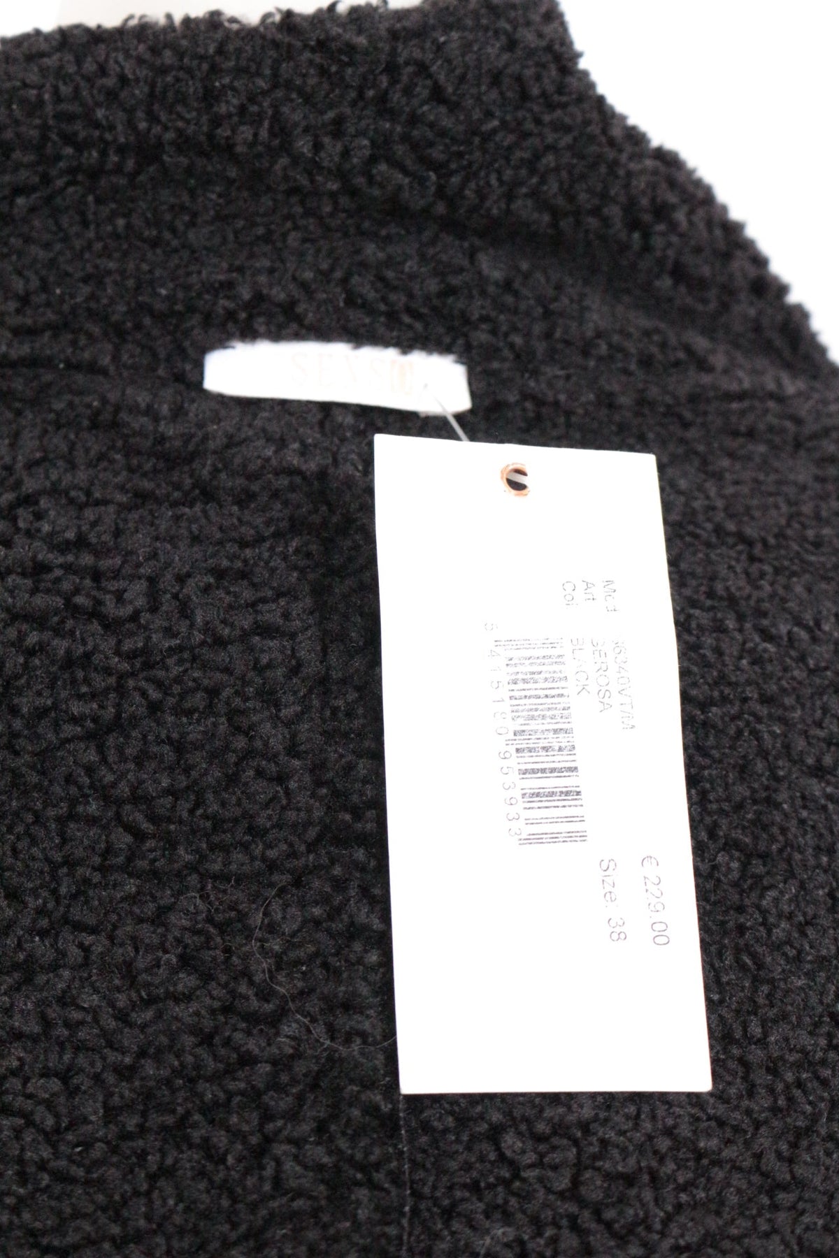 Gros plan sur l'étiquette de la veste Frippindealz Senso en matière effet mouton noir avec étiquette de prix