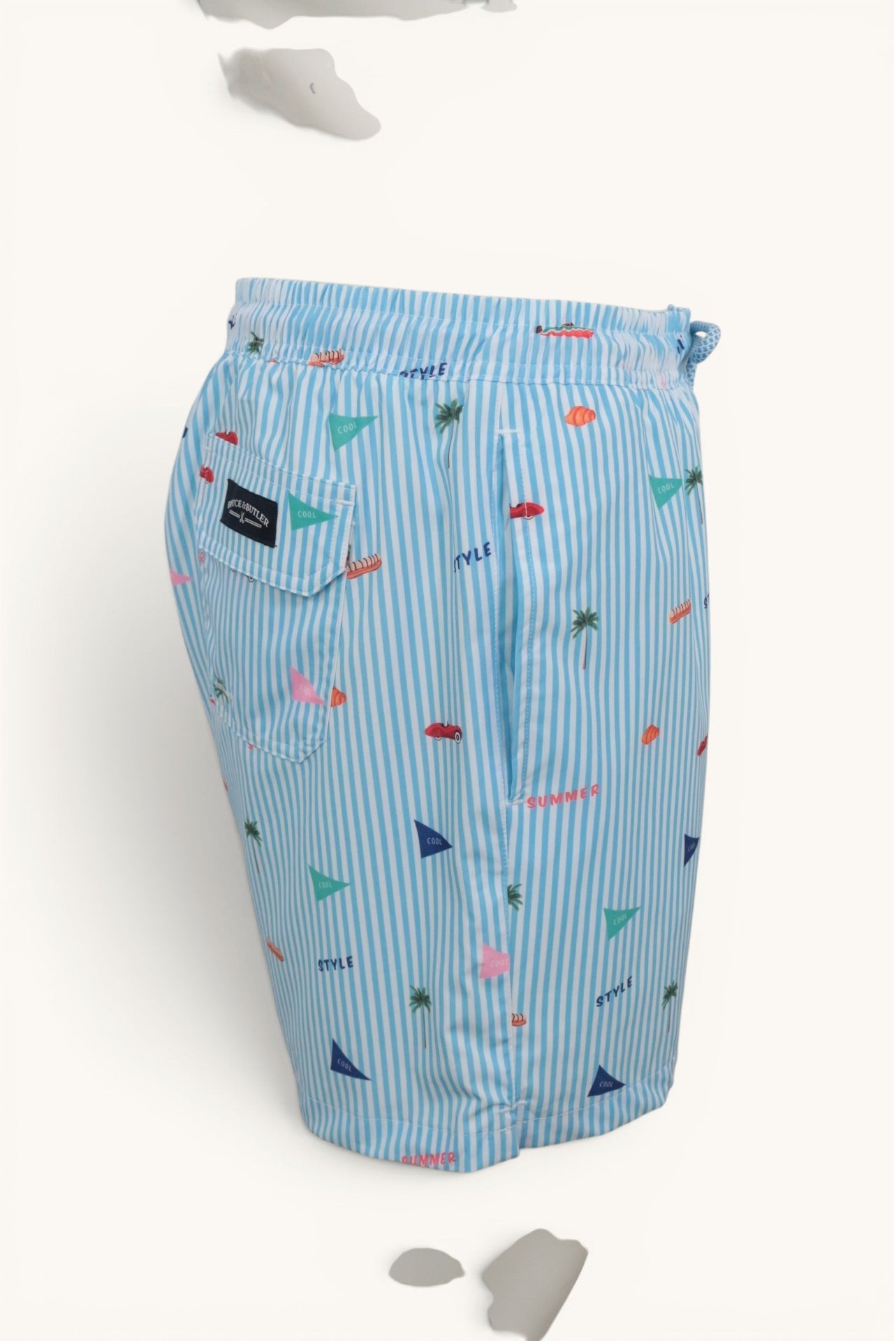 Short de bain Frippindealz Bruce & Butler bleu ciel et blanc à rayures avec motifs estivaux et poche arrière à rabat.