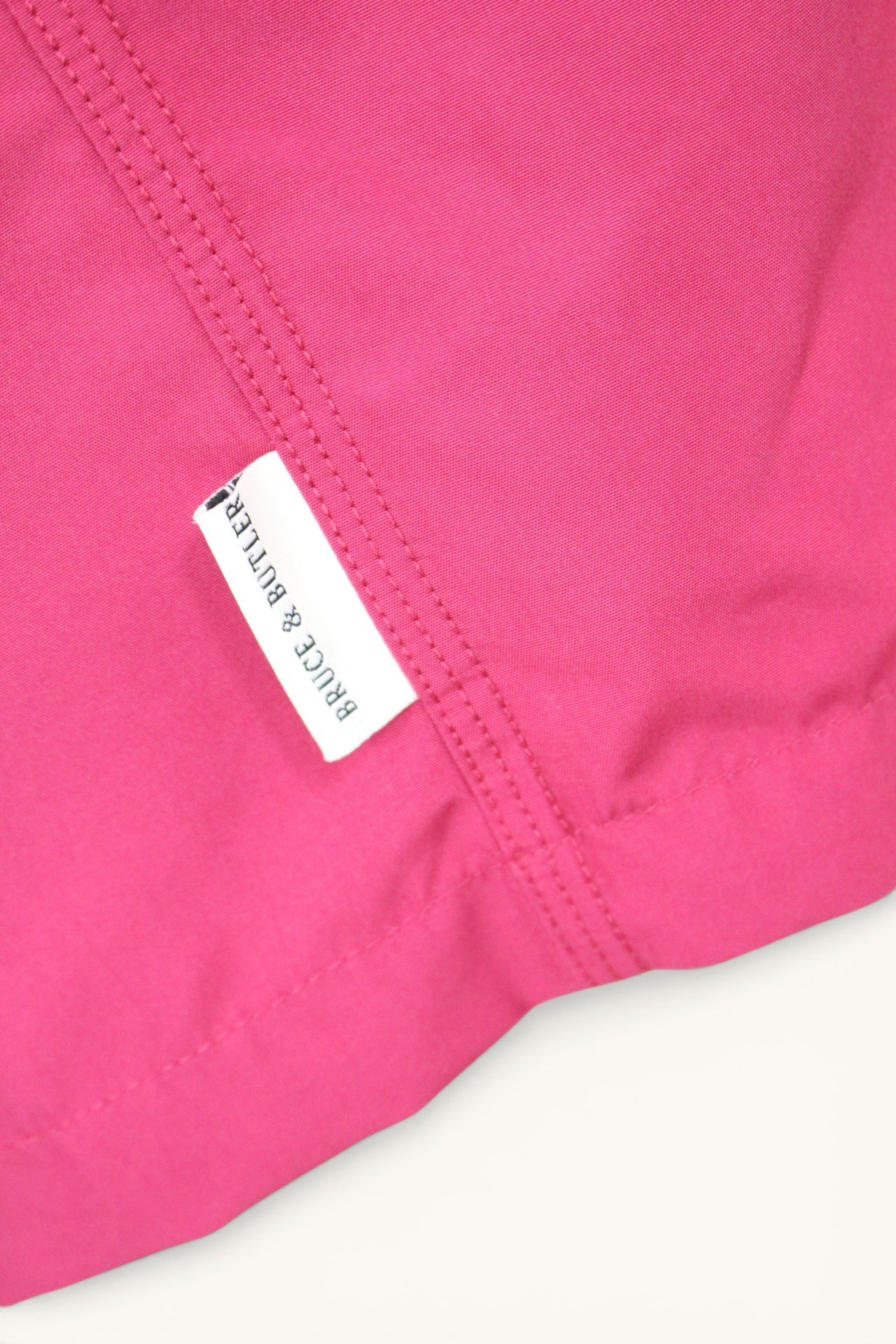 Short de bain Frippindealz rose vif avec étiquette de marque Bruce & Butler cousue, en polyester léger.