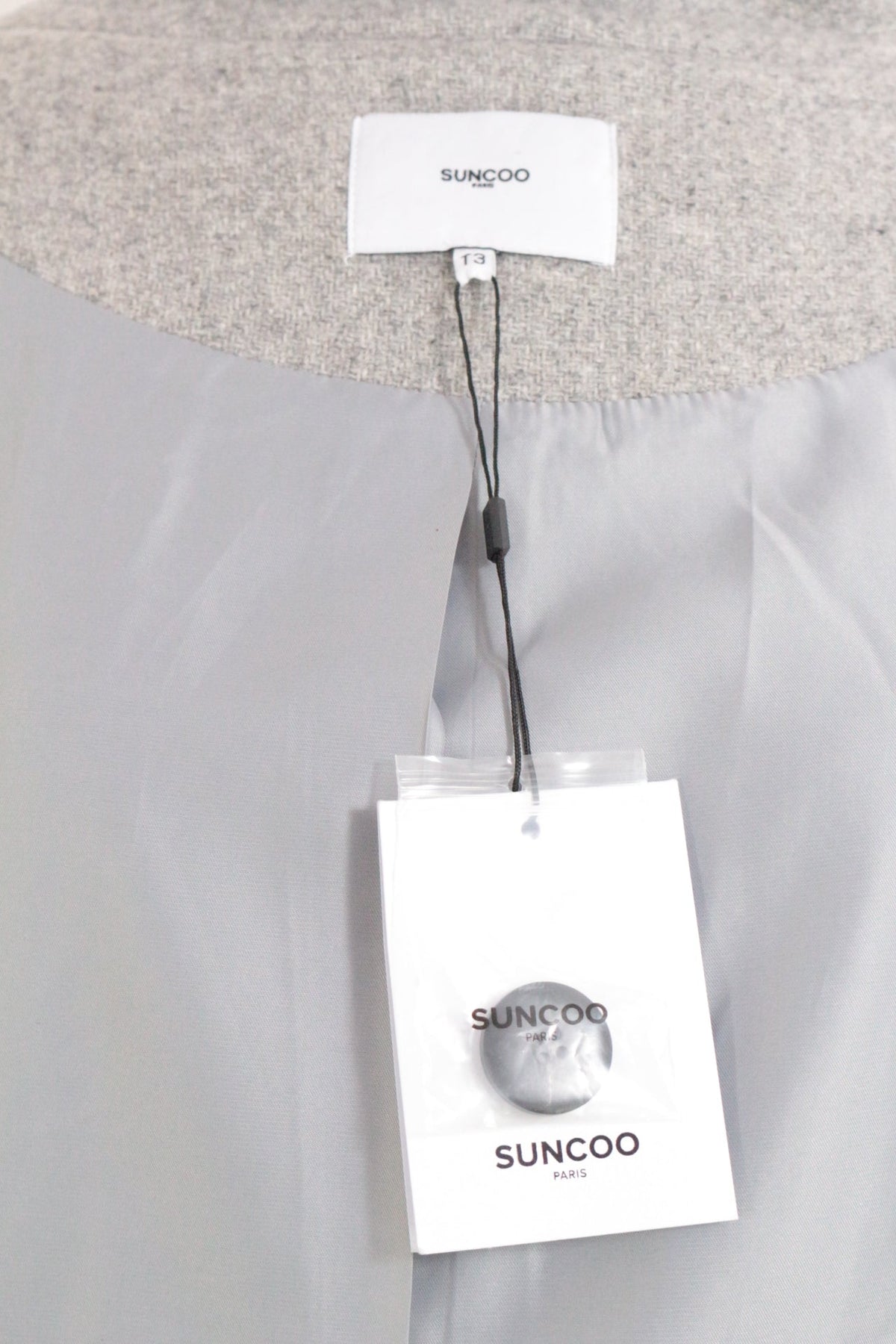 Détail de l'étiquette et doublure intérieure grise d'un manteau Frippindealz Suncoo en laine, neuf avec étiquette
