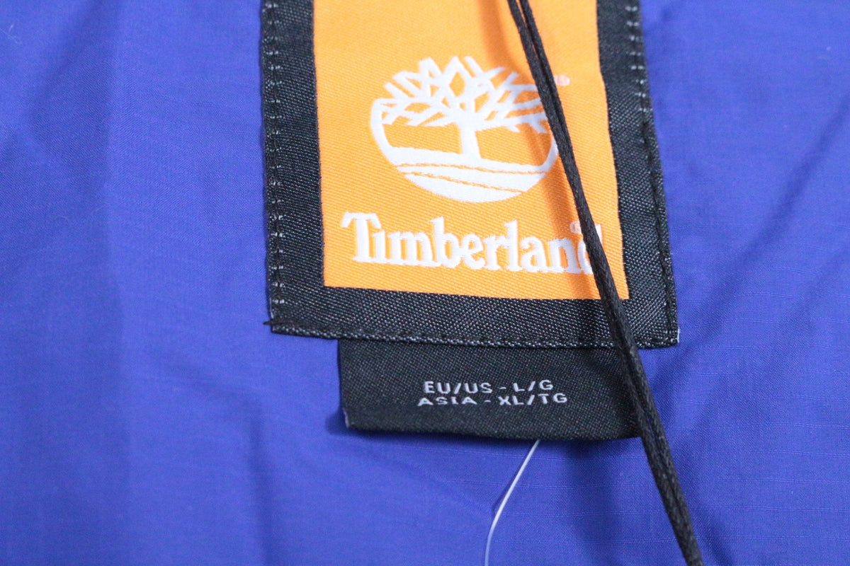Étiquette intérieure Frippindealz sur doudoune bleue Timberland avec logo et taille L