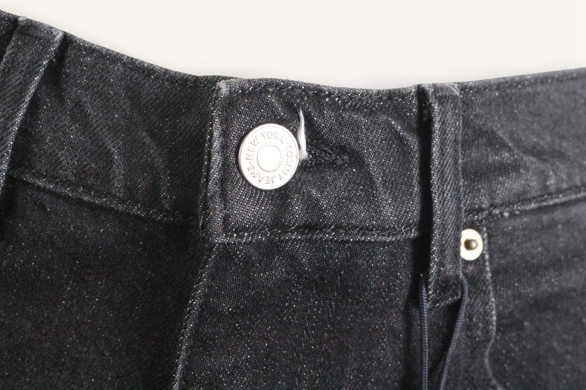 Gros plan sur le bouton métallique gravé d'un pantalon en coton noir Frippindealz Tommy Hilfiger neuf