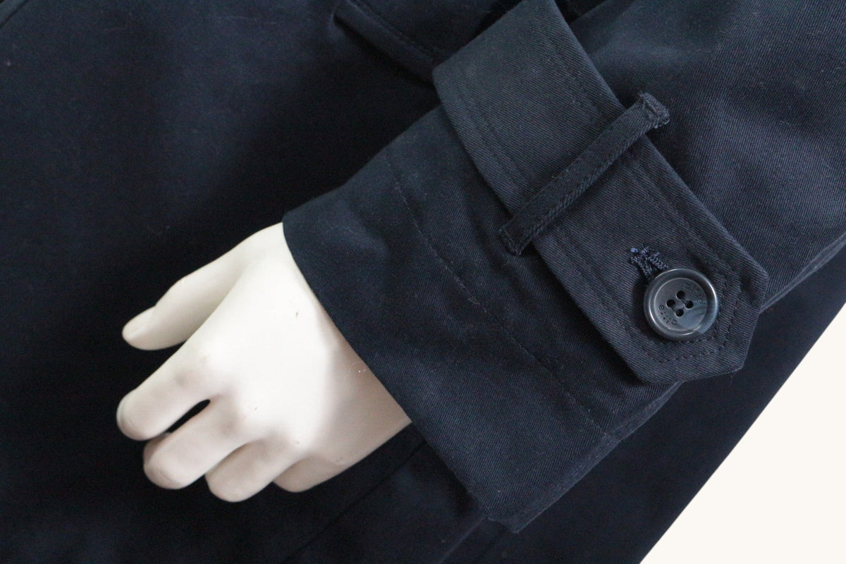 Détail de la manche d'un trench bleu marine Frippindealz en coton avec patte boutonnée sur mannequin