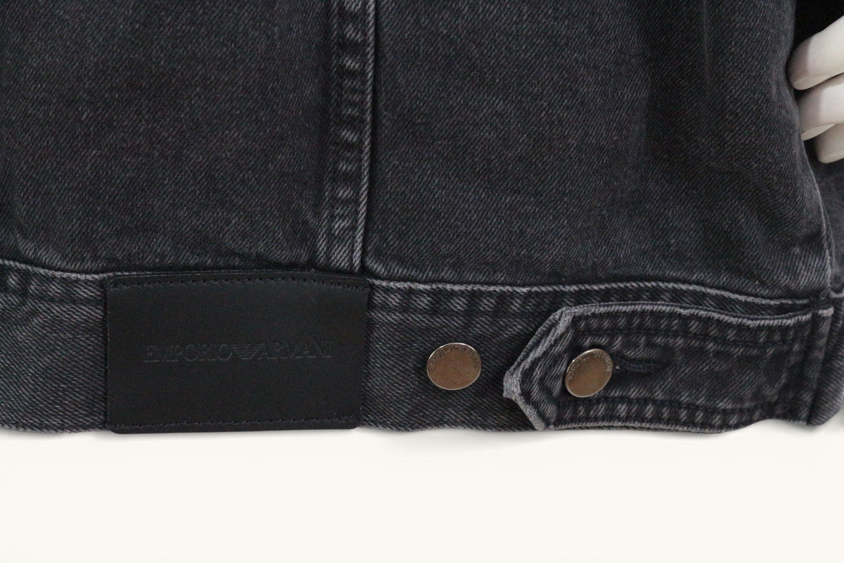 Détail de la veste en denim noir Frippindealz Emporio Armani avec étiquette en cuir et boutons métalliques gravés