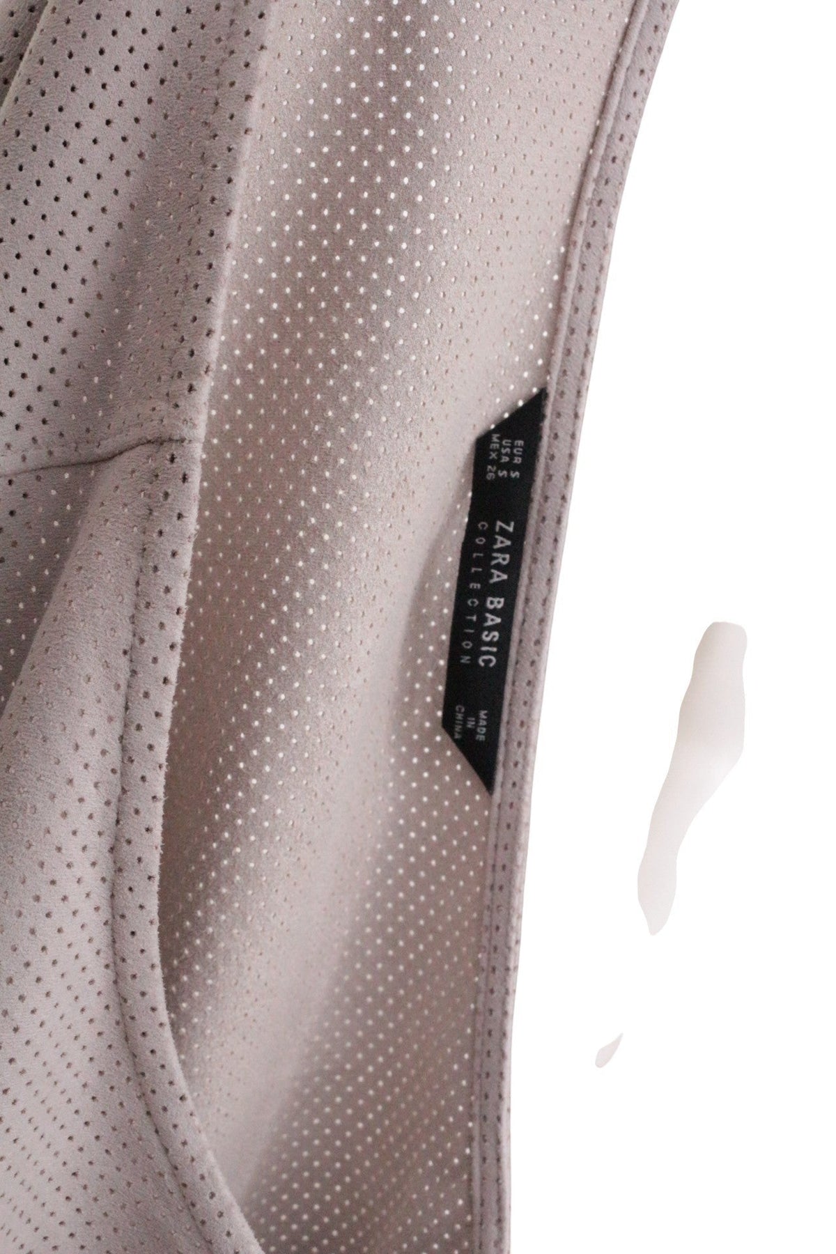 Gros plan sur l'étiquette Frippindealz Zara d'une robe courte beige en polyester perforé effet daim