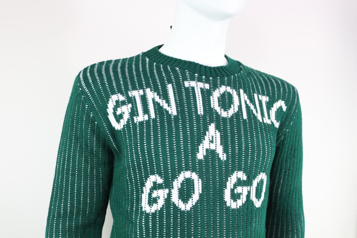 Gros plan sur le col rond et le message Gin Tonic A Go Go du pull Millions Man vert – Frippin'Dealz