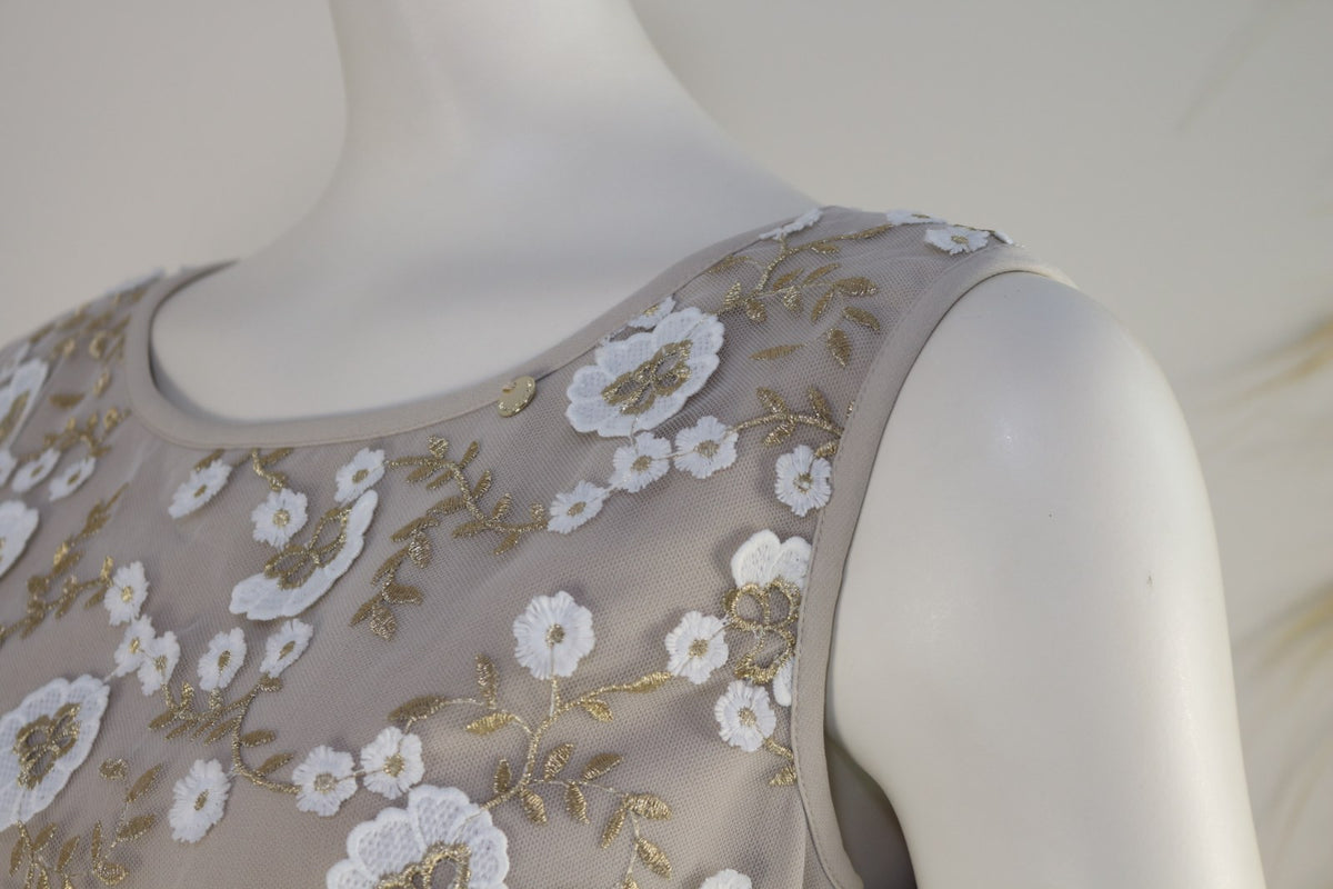 Gros plan sur l'encolure, l'épaule et le médaillon doré de la robe Kitana beige – Frippin'Dealz
