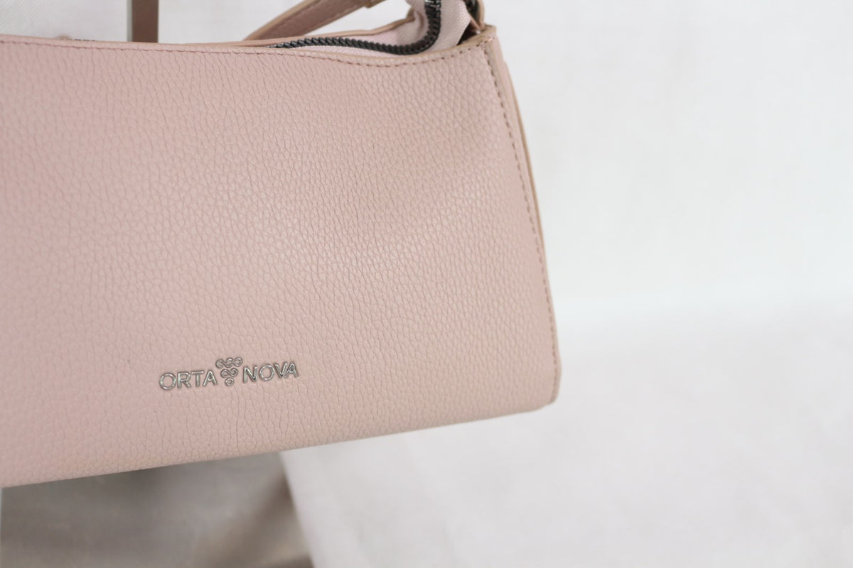 Gros plan sur le logo métal Orta Nova et le grain du sac rose – Frippin'Dealz